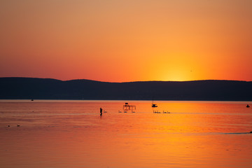 Sunset over lake Balaton in vivid orange color with silhouettes