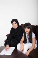 Arab woman teaching her daughter on white background