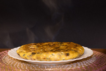 Clásica tortilla de patatas con fondo negro y humo