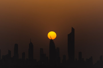 big sun during sunset, sun touching skyscraper