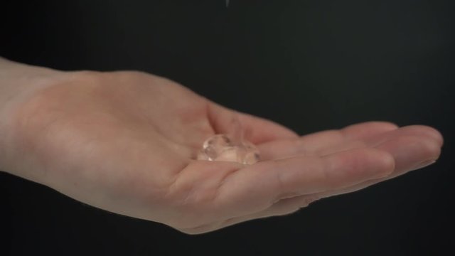 Closeup of releasing cosmetic product in slow motion. Antiseptic gel falling to the woman hand on a black background.