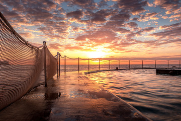 Obraz premium Sunrise at Bronte Beach Pool, New South Wales, Australia. Waves on the rocks.