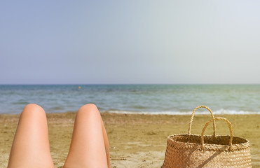 Obraz premium Close-up of young women legs relaxing on beach and tanning . Bright warm filter .