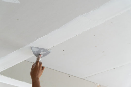 hand of worker using gypsum plaster ceiling joints