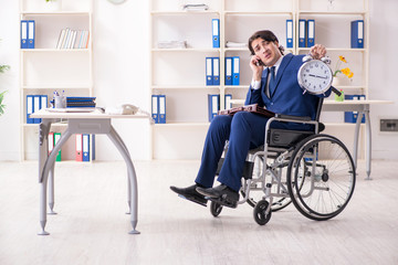 Young male employee in wheelchair working in the office 