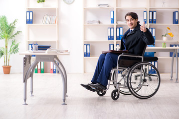 Young male employee in wheelchair working in the office 