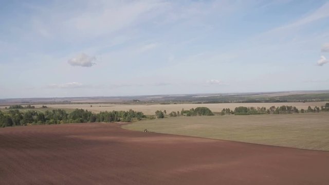 Tractor cultivating land. Aerial view of harvest fields with tractor. Agricultural machinery on plowing field