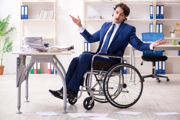 Young male employee in wheelchair working in the office 