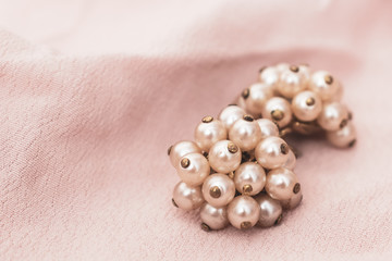 A pair of pearl earrings, bijouterie on delicate pure beige fabric background with copy space