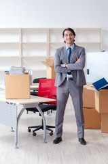 Young man employee with boxes in the office 