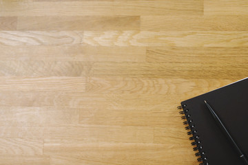 View from above of face sketch notepad color black and a pen on wooden background with copy space. top view blank notebook and text.