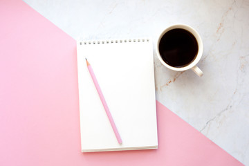 Business Workplace in a minimalist style with cup of coffee, notebook, pencil. Pink and marble background