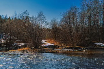 Early Spring landscape melts ice on a small river at the edge of the village.