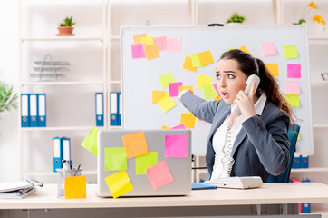 Young female employee in conflicting priorities concept 