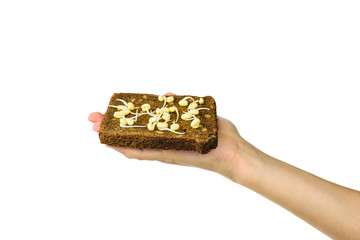 A piece of bread with sprouted mung beans in the hand of a child isolated on a white background.