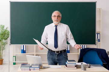 Aged male teacher in front of chalkboard 