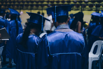Rear view of graduates in blue academic attire. Selected focus. Copy space. - Powered by Adobe