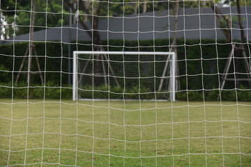 Football /soccer goal gate  with net and green lawn grass background in view behind