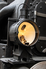 An old lamp of a steam locomotive shines to forward on track. Retro light in front part of train.
