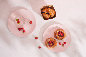 Fototapeta na wymiar Sweet summer dessert, homemade baked mini croissants, served with cold raspberry cider, fresh raspberries. On a white marble table, copy space top view