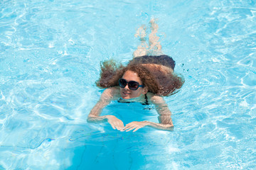 Young girl swims in the pool on a summer day