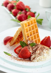 Belgian waffles with strawberries and cream, mint and chocolate chips.