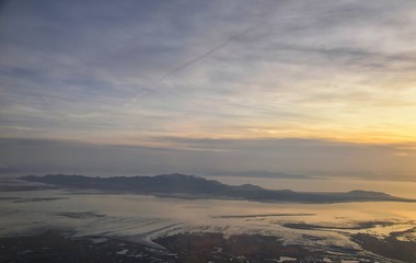 Aerial view from airplane of Antelope Island at sunset, view from Magna, sweeping cloudscape at sunrise with the Great Salt Lake State Park in winter. USA, Utah.