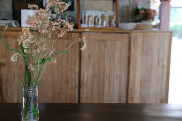 flower in vase on wooden coffee table in cafe