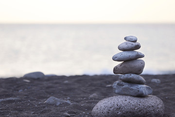 Pyramid of gray stones on the background of the ocean on the beach with black sand in Portugal. Background, texture, close-up, without people, horizontal, plenty of space for text. Nature's concept.