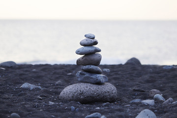 Pyramid of gray stones on the background of the ocean on the beach with black sand in Portugal. Background, texture, close-up, without people, horizontal, plenty of space for text. Nature's concept.