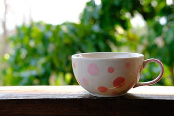 coffee cup on wooden desk table with garden view