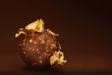 Chocolate praline with edible gold on dark brown background in low key