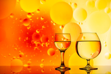 transparent glasses with water and oily drops on colorful background 