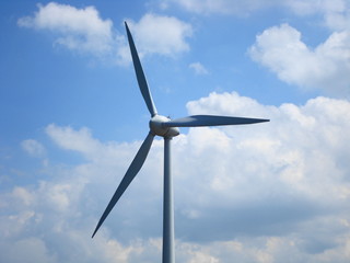 Top of a windmill with a cloudy blue sky