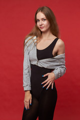 Pretty young sexy fashion sensual woman posing on red wall background,dressed in hipster outfit, stylish trendy brunette hipster in black clothes.Red background, not isolated