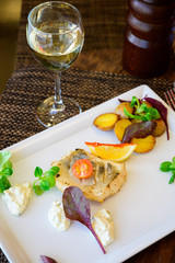 A piece of fish with vegetables and fried potatoes on a plate