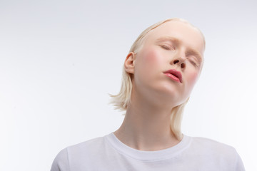 Skinny young model with rosy cheeks closing eyes while posing