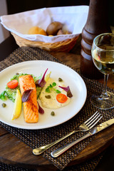 A piece of baked fish with lemon, vegetables and sauce