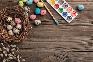 Obraz na płótnie Canvas Colorful easter eggs and brushes on wooden table. Top view