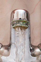 Vertical macro image of a tap with water flowing strongly under high pressure