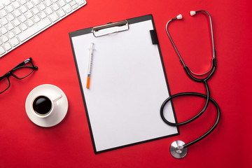 Stethoscope in doctors desk with tablet and coffee cup, top view