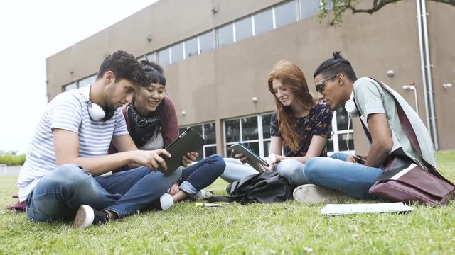 Medium shot of college students using digital tablet in university campus