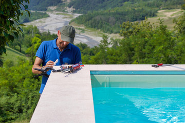 tiler working in a garden building the edge of a pool