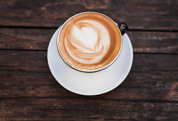 A cup of coffee on a dark wooden table.