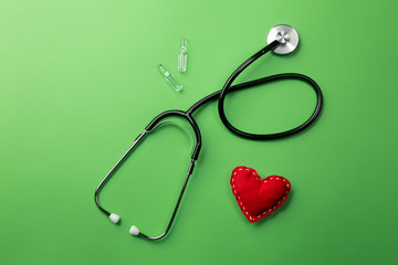Stethoscope in doctors desk with heart, syringe and ampoules