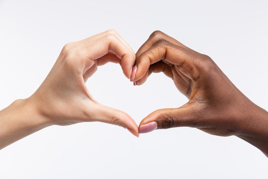 Women with white and black skin showing heart with their hands