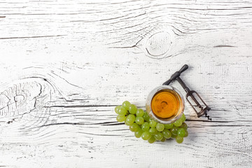 Corkscrew, grape and wineglass on white wooden board