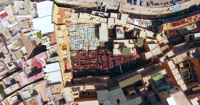 FEZ, MOROCCO. Zoom-out over the tanneries packed with the round stone wells filled with dye. Aerial 4K view on tanning industry working process.