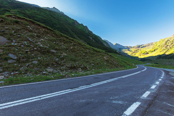 transfagarasan road at sunrise. popular travel destination of romania. beautiful summer landscape in mountains. road winding uphill through gorge with steep rocky cliffs