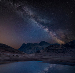 Digital composite image of Milky Way over beautiful landscape image of Blea Tarn in UK Lake District